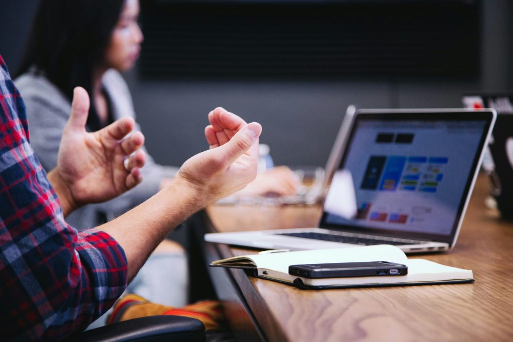 Man gesturing while discussing data on laptop