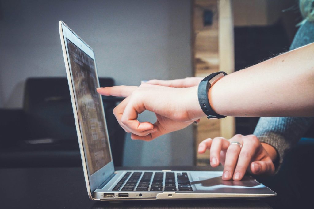 Close-up of hands pointing at laptop screen