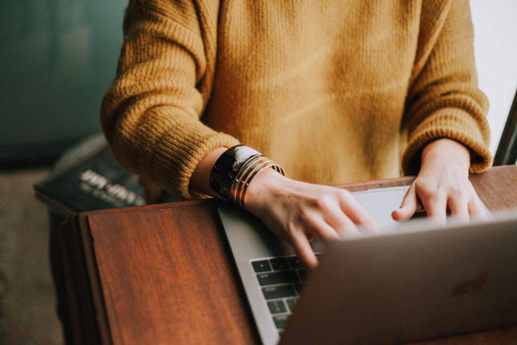 Person typing on laptop wearing a sweater.