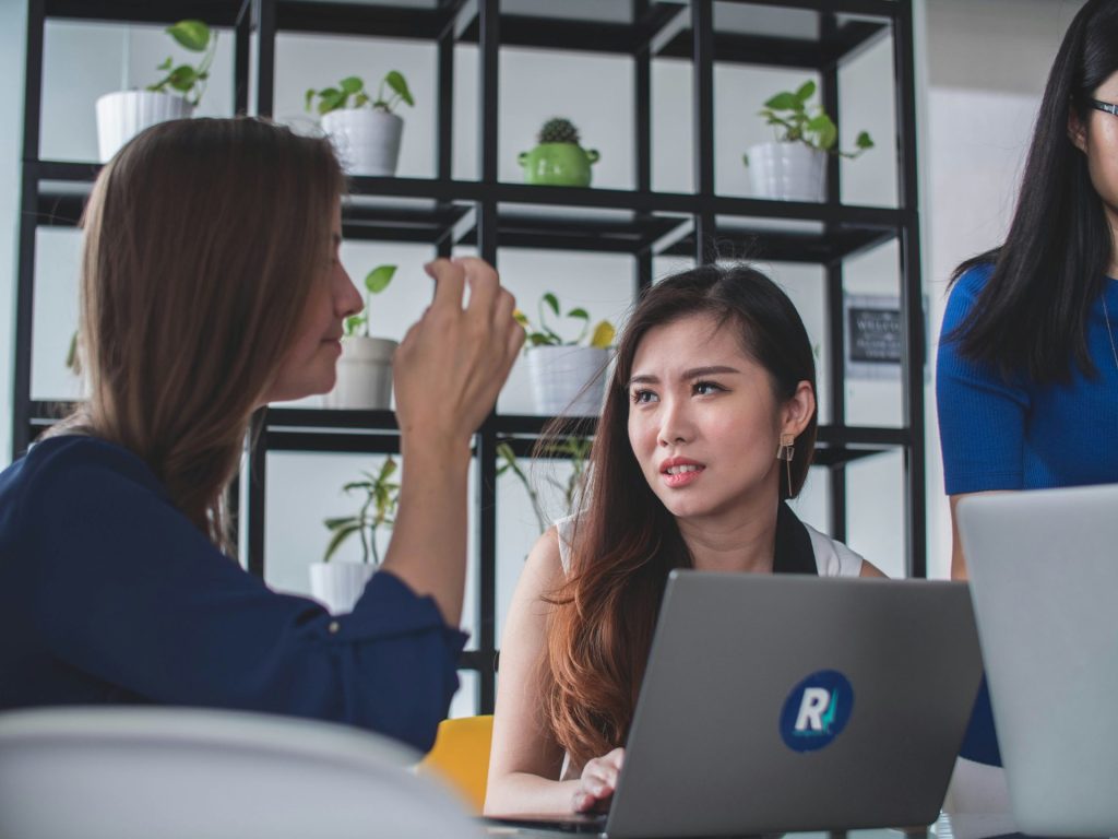 Two women discussing something on laptop