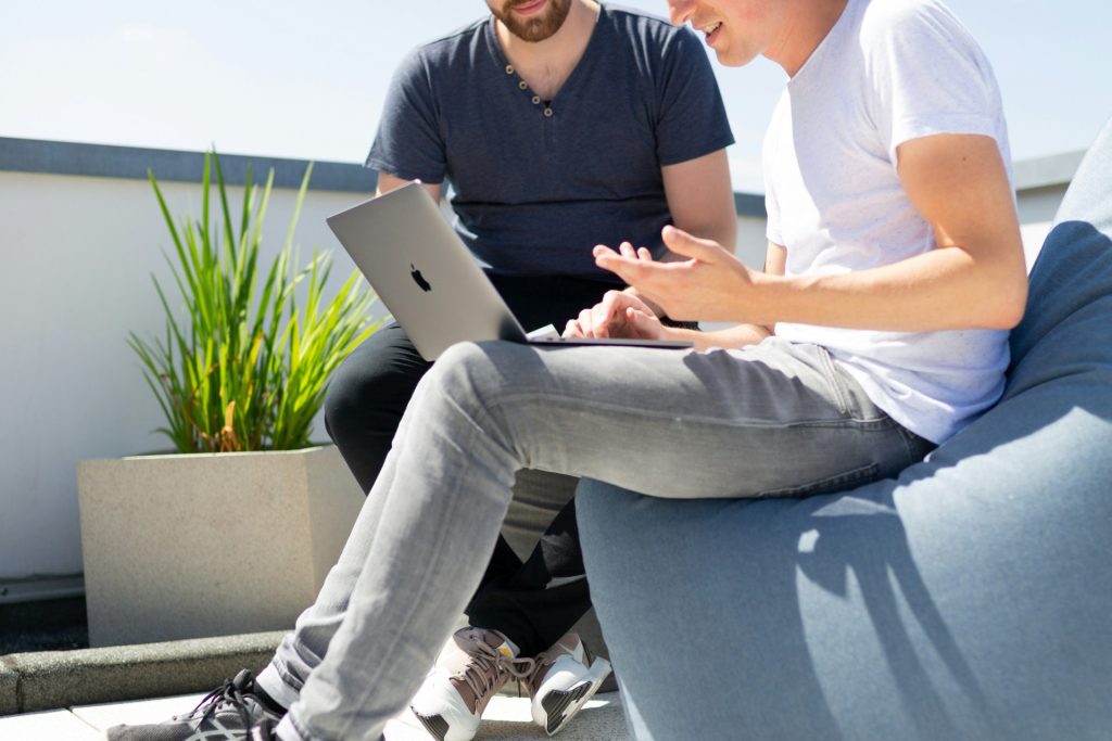 Two men having a discussion outdoors, laptop