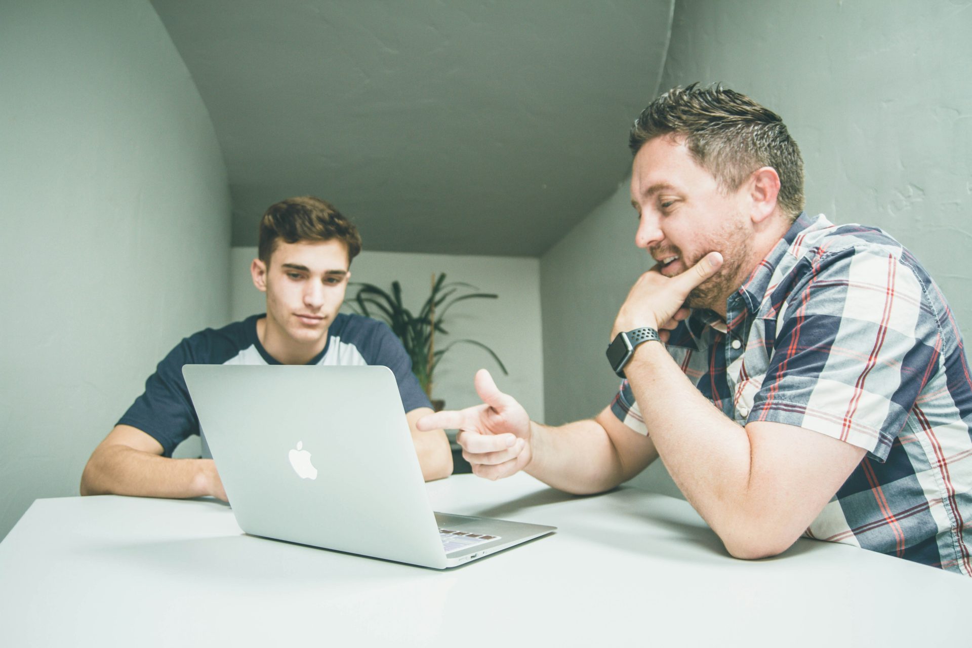 Two men in discussion, pointing at laptop